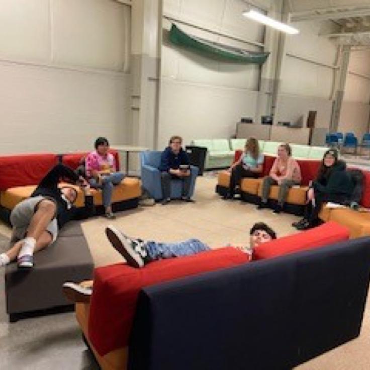 A group of teenagers lounging on sofas arranged in a circle