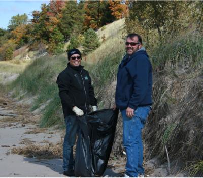 Two men collecting trash on the beach